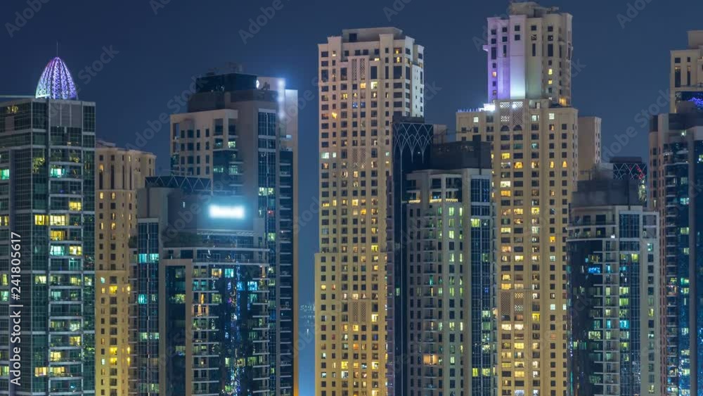 Glowing windows in multistory modern glass and metal residential buildings light up at night timelapse. Glowing windows in multistory modern glass and metal residential buildings light up at night timelapse.