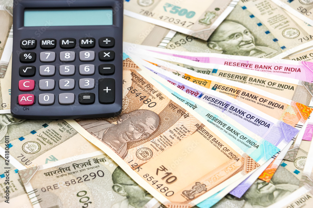 Close up view of calculator over brand new indian 10, 50, 100, 200, 500 and 2000 rupees banknotes. Colorful money background. Close up view of calculator over brand new indian 10, 50, 100, 200, 500 and 2000 rupees banknotes. Colorful money background.