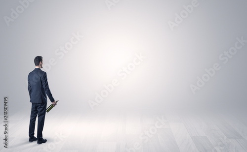 Man standing with his back in an empty room with object in his hand © ra2 studio