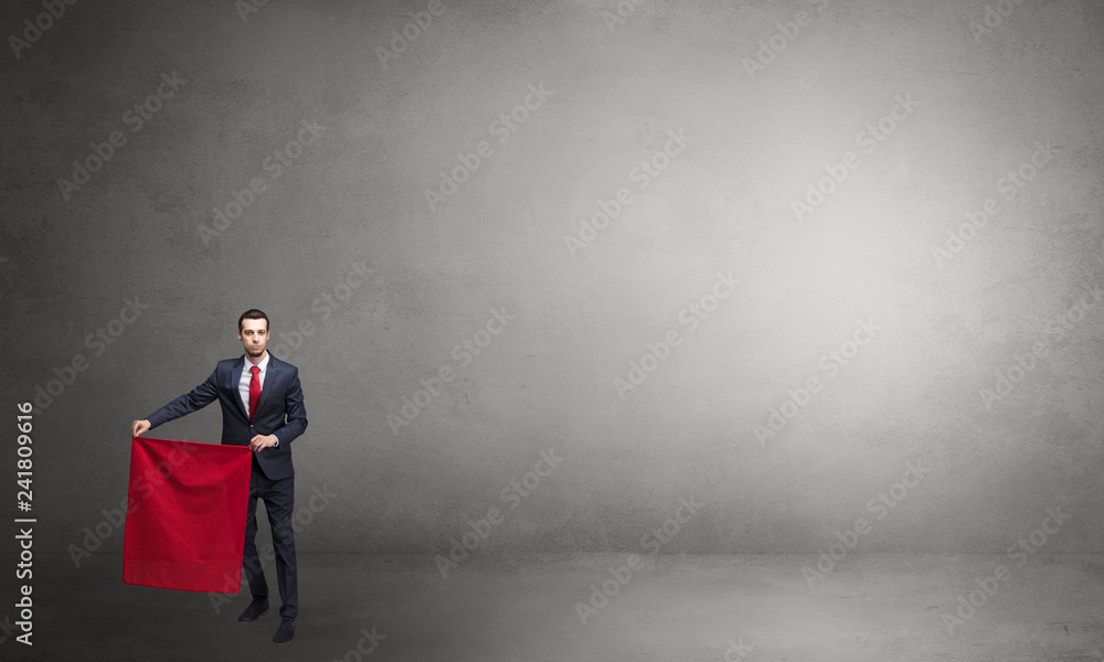 Obraz premium Businessman standing with red toreador cloth in his hand in an empty room 