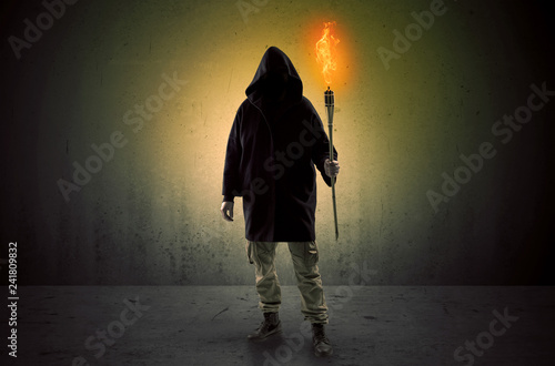 Ugly scary man with burning flambeau walking in an empty space