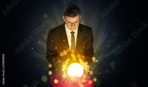 Gorgeous businessman sitting with sparkling magic ball in his lap 