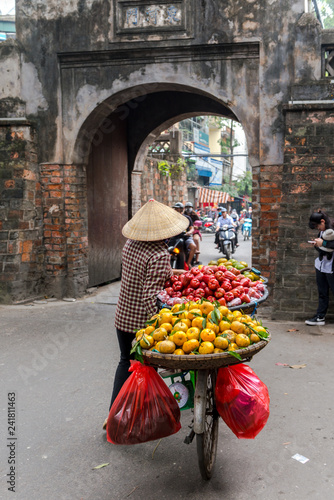 Woman is selling fruits from bicycle on the street in Hanoi Vietnam.