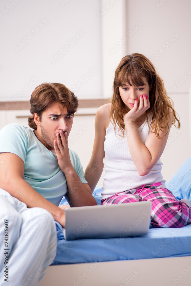Young couple with laptop in the bedroom Young couple with laptop in the bedroom