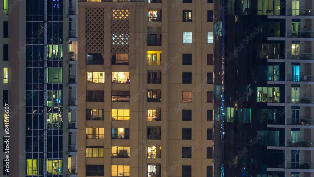 Glowing windows in multistory modern glass and metal residential building light up at night timelapse. Glowing windows in multistory modern glass and metal residential building light up at night timelapse.
