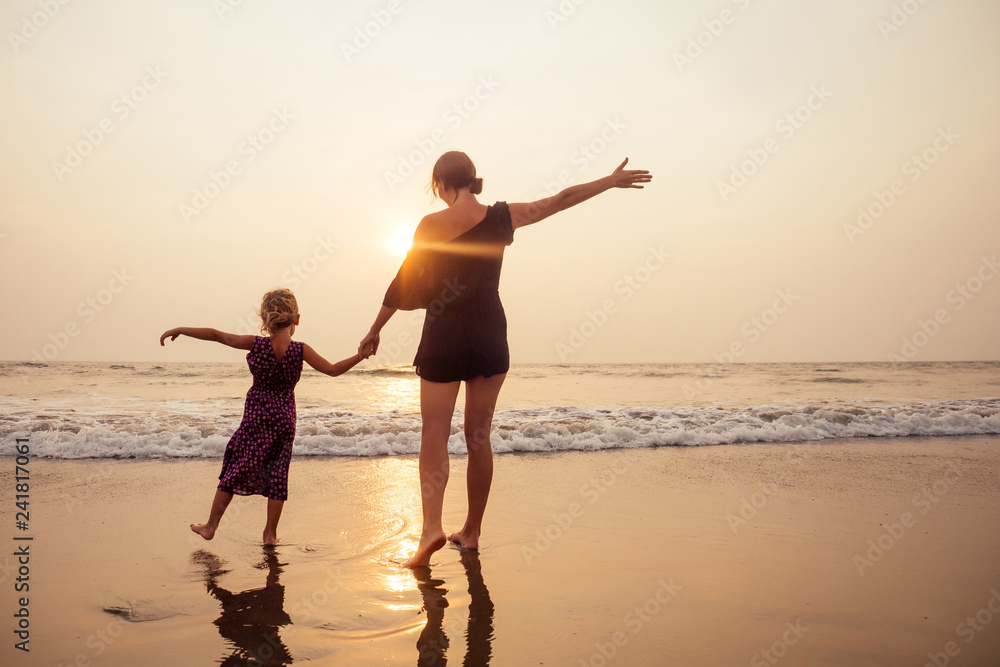 Fototapeta premium happy family at the beach. mother hugging child daughter and fly tourism with children