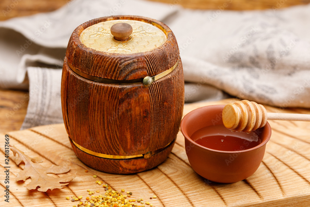 A small wooden barrel with honey inside and a spoon on a wooden table. Barrel. Rustic still life. A small wooden barrel with honey inside and a spoon on a wooden table. Barrel. Rustic still life.
