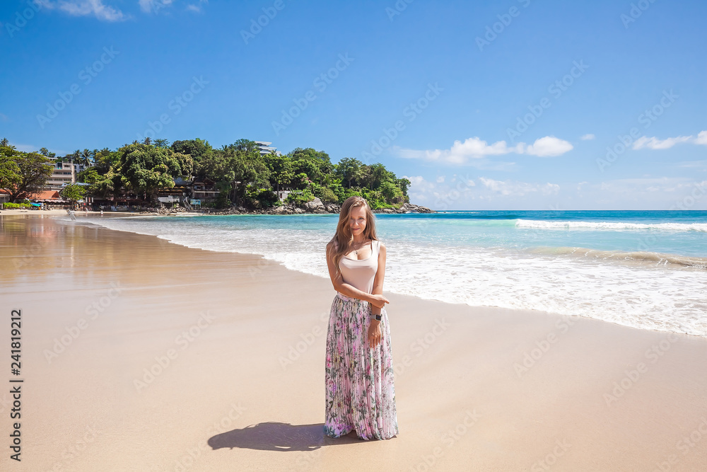 Girl wearing floral pink maxi skirt standing barefoot on the sea shore while sky is incredible blue, Thailand, Phuket Girl wearing floral pink maxi skirt standing barefoot on the sea shore while sky is incredible blue, Thailand, Phuket