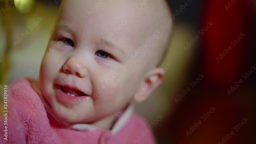 funny little baby is viewing shiny garland and smiling, close-up of kid face funny little baby is viewing shiny garland and smiling, close-up of kid face