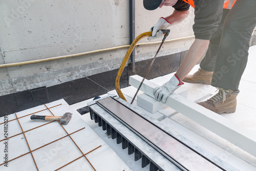 Waterproofing and thermal insulation of a terrace - roof. Professional worker, near a drain gully for drainage, is preparing a layer of extruded polystyrene insulating photo