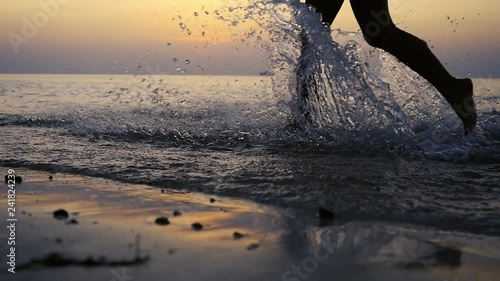 Female feet run in sunset sea close up in slow motion. 1920x1080 photo