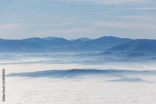 Fog filling a valley in Umbria  Italy   with layers of mountains and hills and various shades of blue