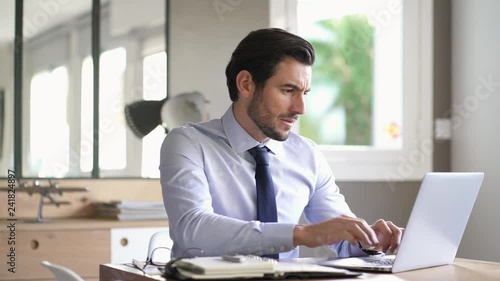 Handsome businessman concentrating on laptop in modern office 