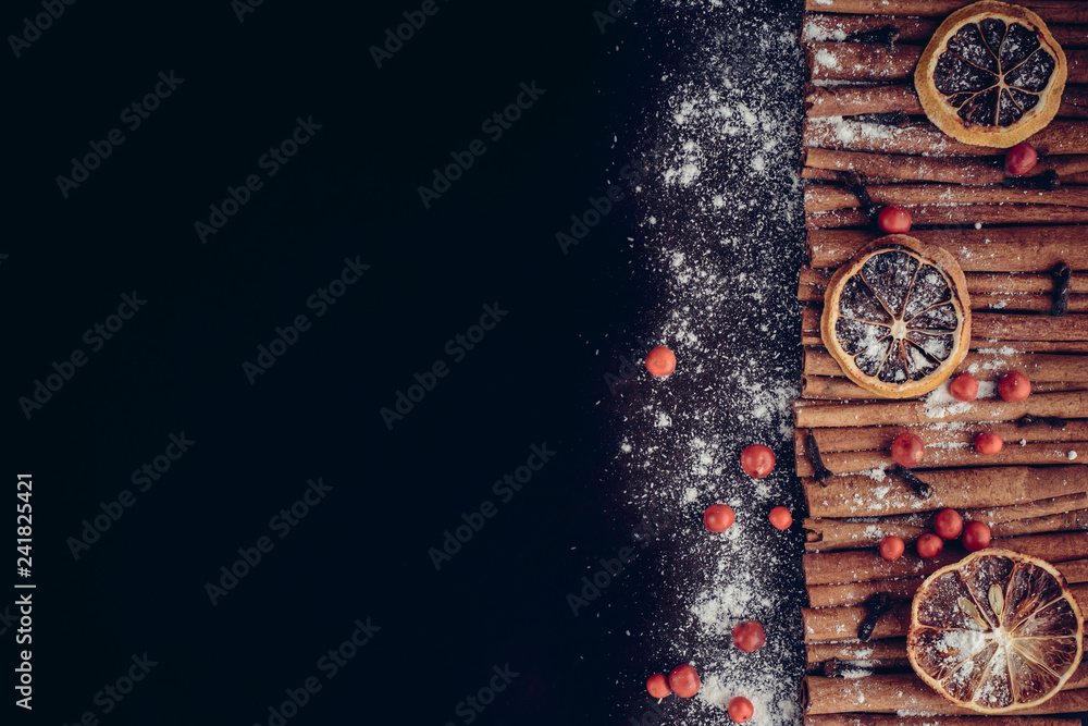 Christmas bakery and New Year concept. Holiday background with dried lemon citrus slices, set of cinnamon sticks and vanilla powder. Cosy winter holiday baking, mulled wine frame on dark background.