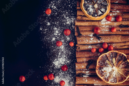 Christmas bakery and New Year concept. Holiday background with dried lemon citrus slices, set of cinnamon sticks and vanilla powder. Cosy winter holiday baking, mulled wine frame on dark background.