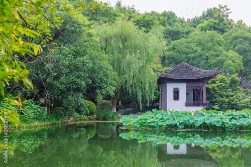 Landscape with trees and Chinese house and reflections in water near West Lake, Hangzhou, China
