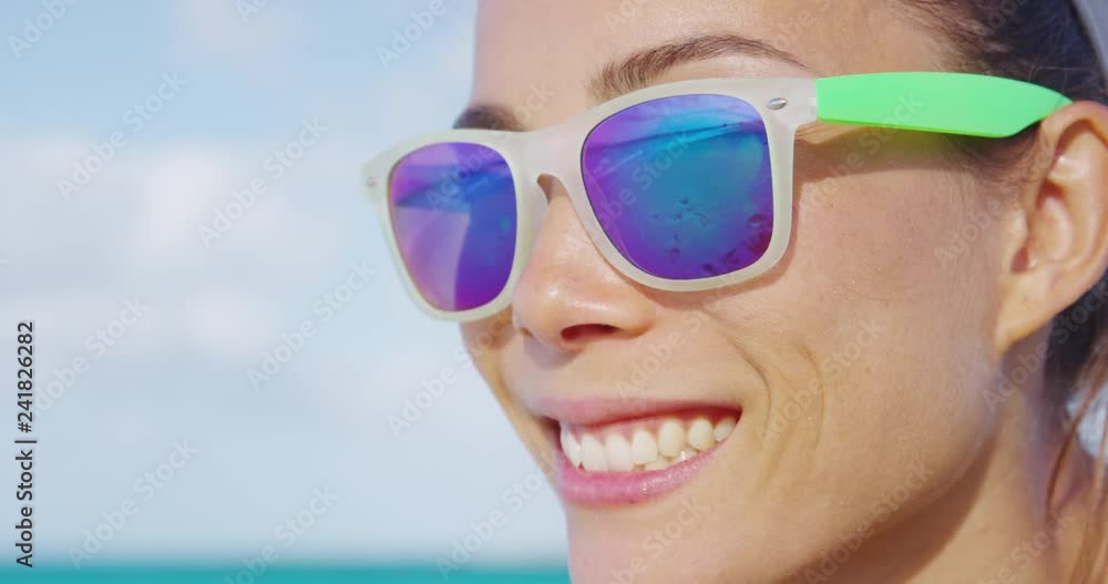 Woman smiling on summer beach wearing sunglasses. Face closeup of funky happy girl having fun in summertime. Woman smiling on summer beach wearing sunglasses. Face closeup of funky happy girl having fun in summertime.