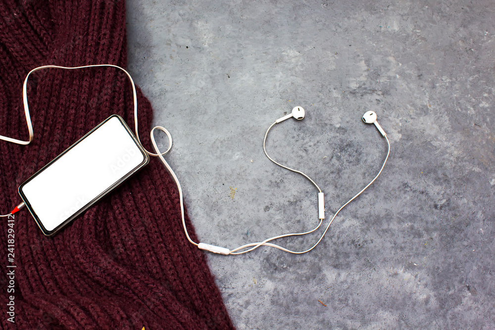Creative flat lay photo of workspace desk with earphones and mobile phone above purple winter Woolen scarf Creative flat lay photo of workspace desk with earphones and mobile phone above purple winter Woolen scarf
