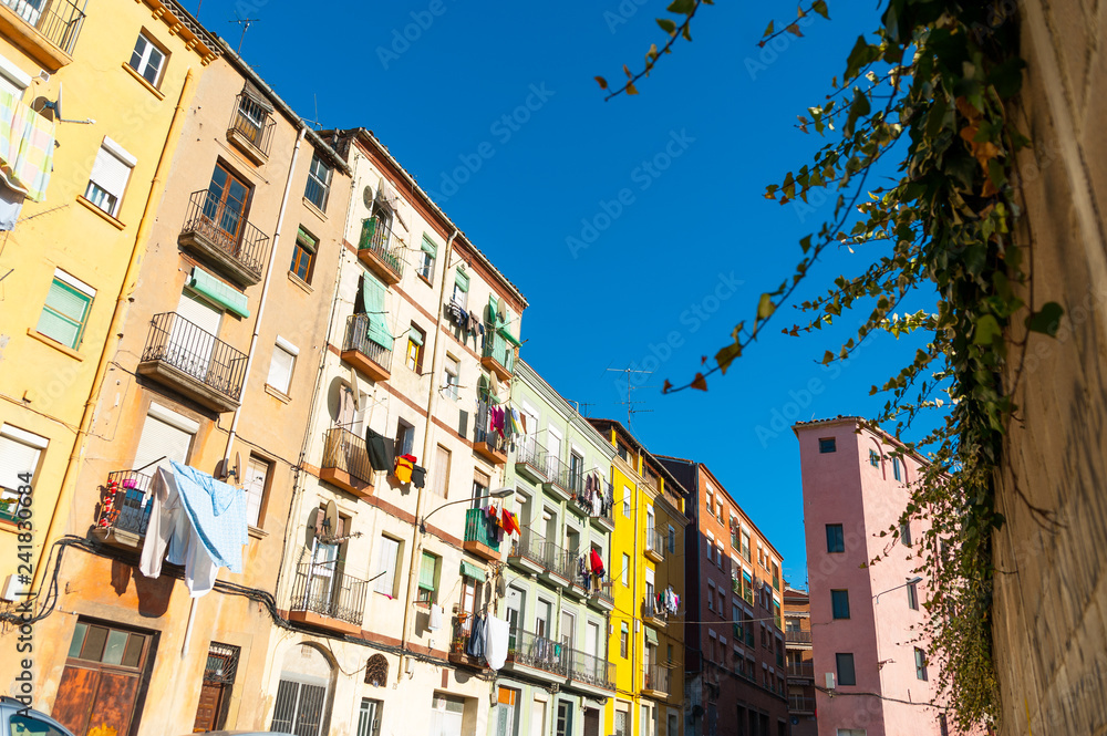 view of street with colorful houses in small catalan spanish medieval town during sunny spring day and clear blue sky