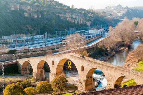 view of Manresa town old bridge, symbol of medieval architecture of the small catalan town, during sunny winter day with yellow ribbon photo