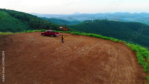 A young man traveling with a small backpack and a red pickup truck