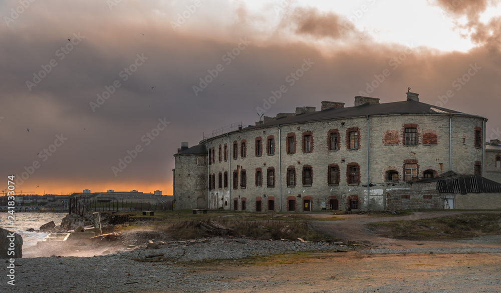 Old building on the shore of the Summer Harbor in Tallinn, Estonia. Bastion. On the windows are iron bars. Autumn evening in the harbor. View of the city in the sunset rays. Clouds cover the sky