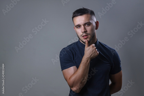 Portrait of a thoughtful look man. Handsome young man thinking on something his hand is near the mouth, isolated on gray background