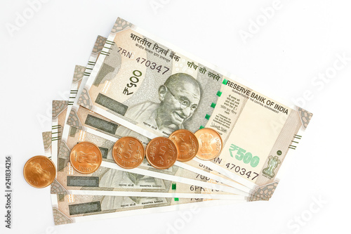 Close up view of brand new indian 500 rupees banknotes and coins on white background.