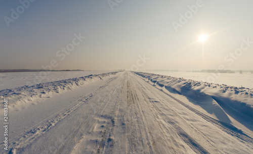 Winter landscape in a cold day with a straight icy road leading forward to horizon