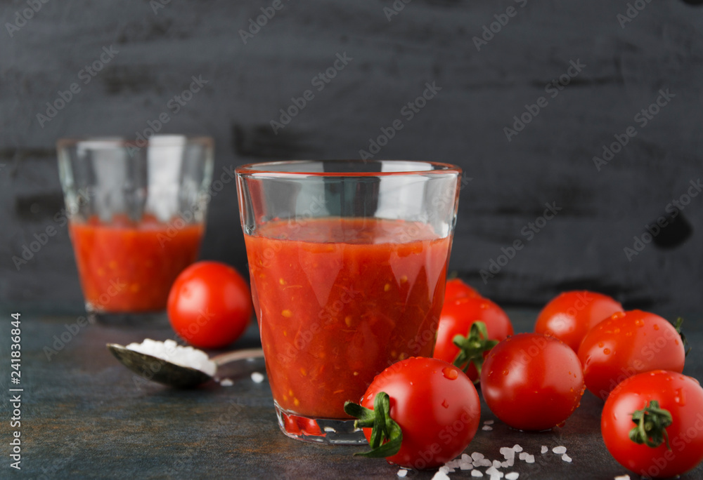 Two glasses of fresh tomatoes juice with salt, cherry tomatoes on dark background Two glasses of fresh tomatoes juice with salt, cherry tomatoes on dark background
