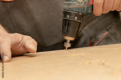 The furniture maker drills furniture blanks with a cordless drill.