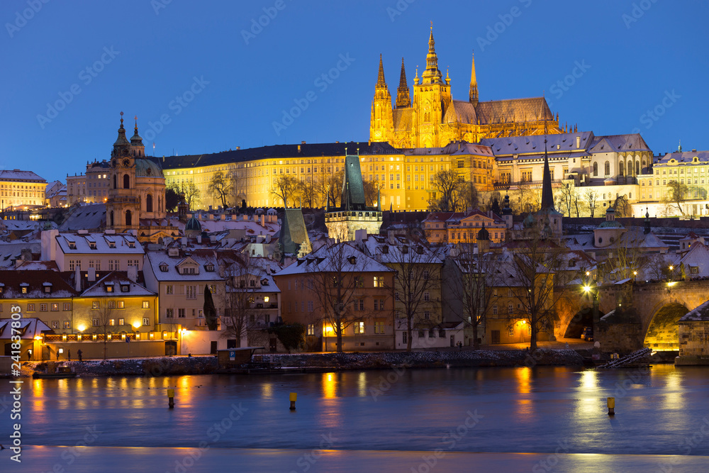 Fototapeta premium Night colorful snowy Christmas Prague Lesser Town with gothic Castle and Charles Bridge, Czech republic