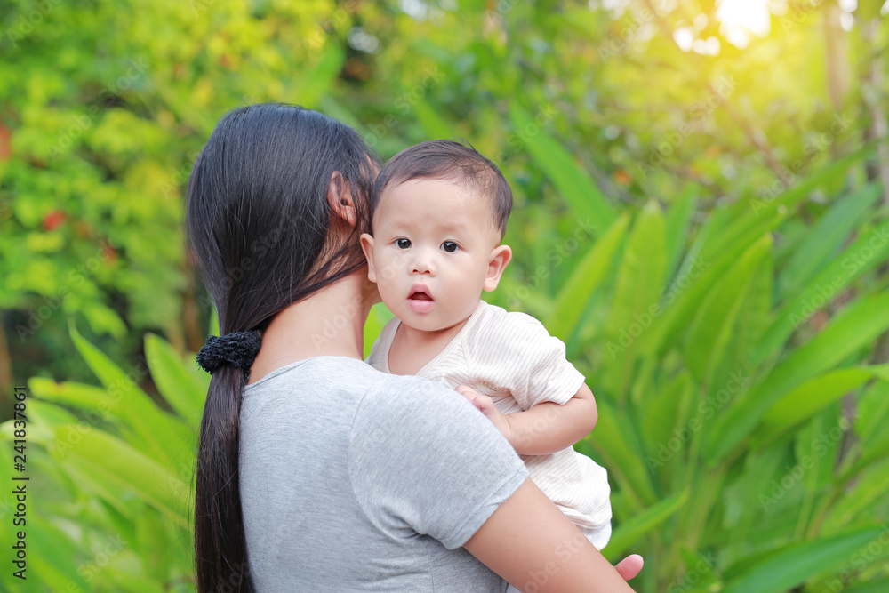 Asian mother carrying her infant baby boy in the green garden. Asian mother carrying her infant baby boy in the green garden.