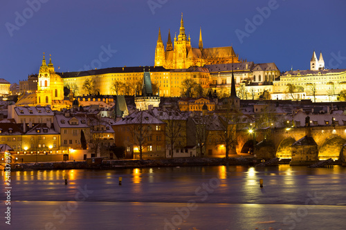 Night colorful snowy Christmas Prague Lesser Town with gothic Castle and Charles Bridge, Czech republic