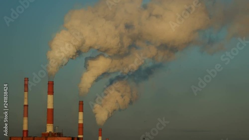 Industrial zone with a large red and white pipe thick white smoke is poured from the factory pipe in contrast to the sun. Pollution of the environment: a pipe with smoke. Seamless cinemagraph video