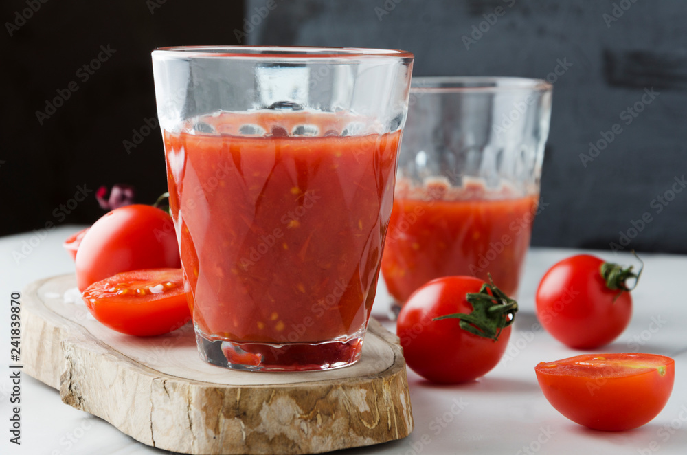 Closeup of glass of fresh pressed tomato juice on table in the kitchen.Tomatos,wooden board,glasses of tomato juice Closeup of glass of fresh pressed tomato juice on table in the kitchen.Tomatos,wooden board,glasses of tomato juice