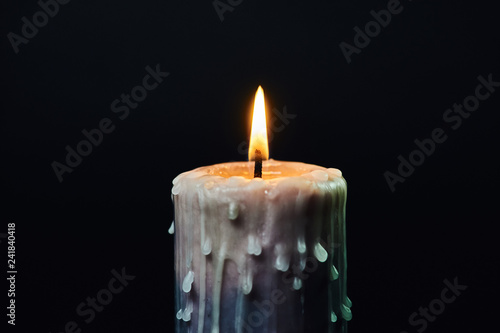 colored candle with drips of wax burns in the dark