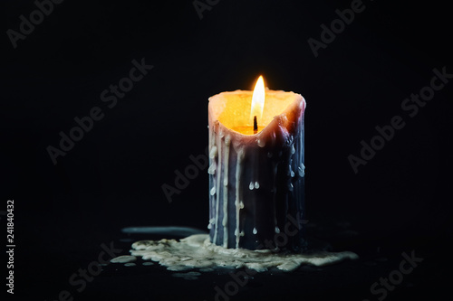colored candle with drips of wax burns in the dark