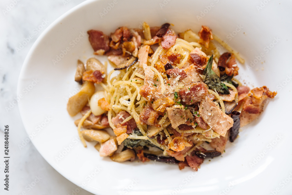 Top view of Dried Spaghetti Chili Bacon served in white bowl plate on marble table. Top view of Dried Spaghetti Chili Bacon served in white bowl plate on marble table.