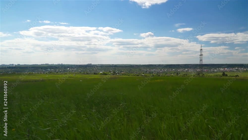 Green field and the village behind. Summer rural landscape. City on the horizon. Green field and the village behind. Summer rural landscape. City on the horizon.