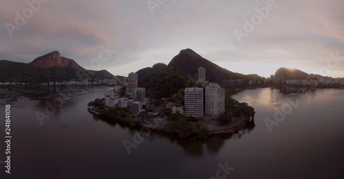 High vantage point view of the city lake in the middle of Rio de Janeiro south neighbourhoods at sunrise with the Corcovado mountain on the right on top of which the Christ statue resides