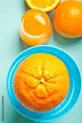 oranges with manual juicer like preparation of orange juice juice in glass over aquamarine background 