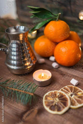 New year's still life with fresh mandarines, lighted candle and cofee turka on wooden background