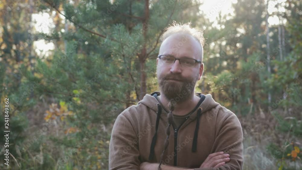 Crazy psychopath with a beard and glasses looking at the camera expressive and evil eyes and wants to kill you on the background of the forest. The concept of violence and cruelty Crazy psychopath with a beard and glasses looking at the camera expressive and evil eyes and wants to kill you on the background of the forest. The concept of violence and cruelty