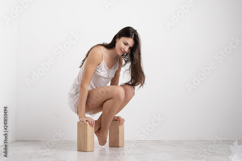 Woman in home clothes doing exercises on the floor. Balances on the blocks.
