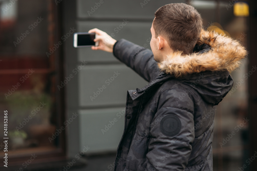 Man in a gray jacket is standing outside and using a phone. Winter Man in a gray jacket is standing outside and using a phone. Winter