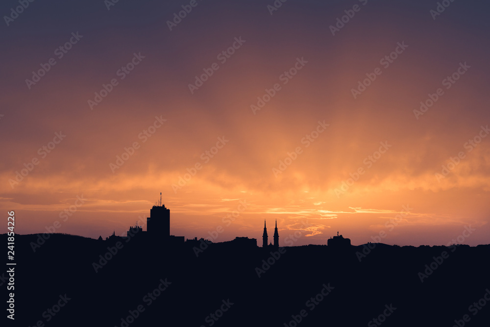 Beautiful sunset sky, evening cityscape. Silhouette of the buildings over colorful cloudy sky background