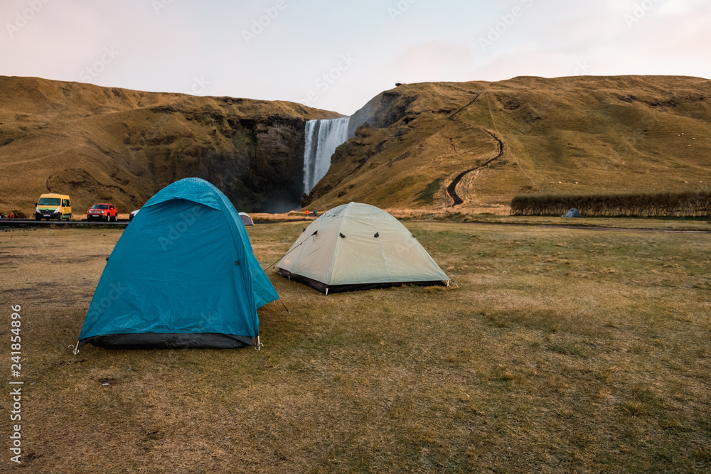 Camping tents near waterfall, Iceland. Nordic nature. 