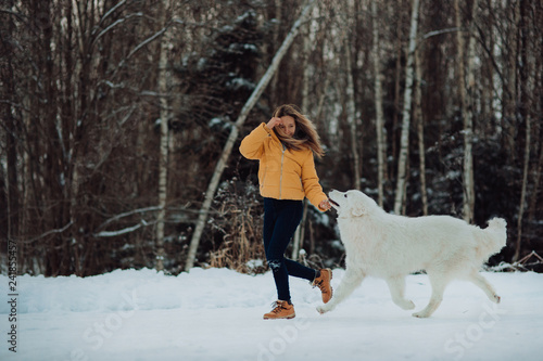 girl teaches how to right run a dog in winter park. The girl with the Maremma . Forest on background
