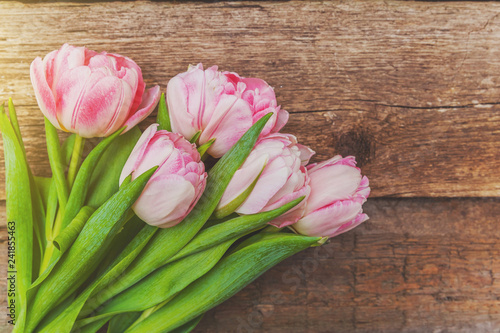 Fototapeta Naklejka Na Ścianę i Meble -  Spring greeting card. Bouquet of fresh light pastel pink tulips flowers on wooden background. Happy holiday easter mother day anniversary valentine day birthday concept. Flat lay top view copy space